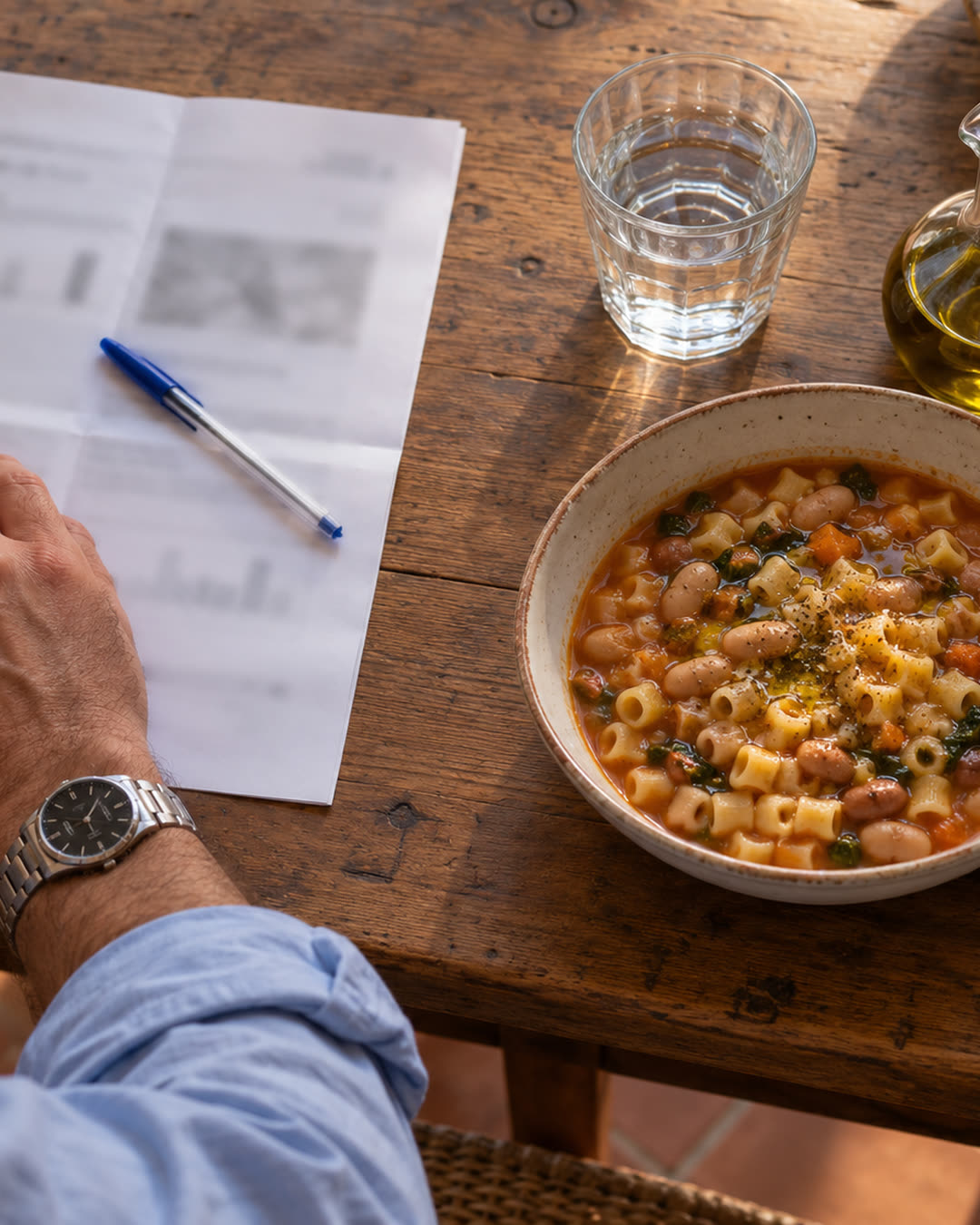 Il tavolo di cucina dall'alto: il foglio delle analisi piegato con la penna e un piatto di pasta e fagioli